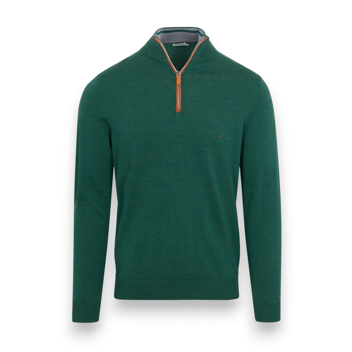 A man in white pants stands before a large fallen tree in the forest, wearing the COLLARS AND CO Hunter Green with Brown Suede Trim Cashmere Touch Australian Merino Wool Sweater, with one hand in his pocket and a brown leather backpack by his side.