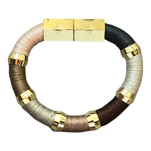 Introducing the HOLST + LEE - COLORBLOCK BRACELET by HOLST & LEE: a circular, multicolored accessory featuring sections of black, beige, and brown materials. This stunning bracelet is embellished with gold rings and a rectangular gold-plated magnetic clasp, seamlessly combining metallic elements with soft textured segments crafted from pearl cotton thread.