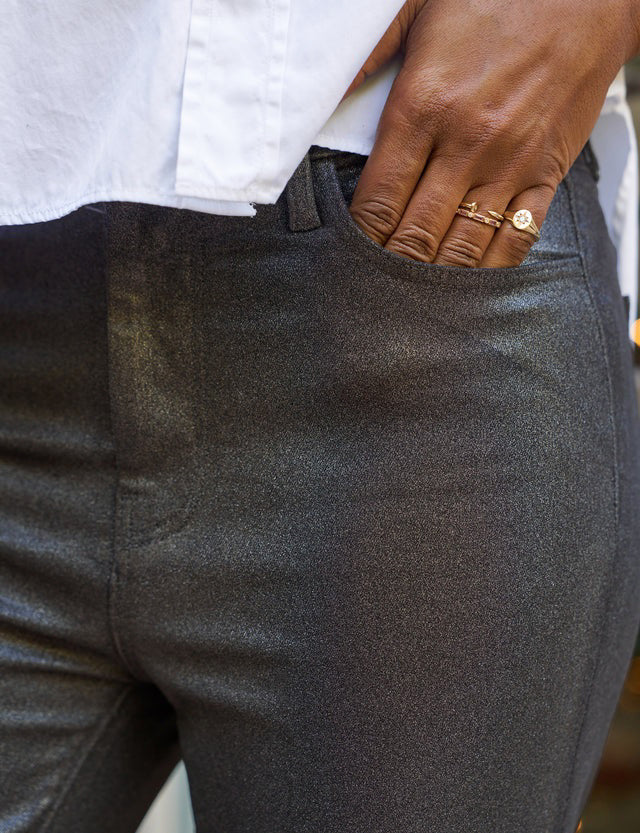 FRANK &amp; EILEEN&#39;s SLIGO SKINNY JEAN IN BLACK METALIC is showcased against a light textured backdrop. It features a high-rise contour waistband, front and back pockets, a button closure, and a shiny waxed denim finish.