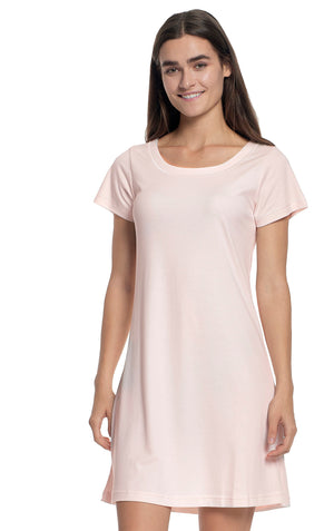 A woman with long hair is wearing the FASHIONVIEWS P. JAMAS - BUTTERKNIT SHORT SLEEVE GOWN in light pink. She is smiling and facing forward. The gown, made from 100% Pima Cotton, features a simple, comfortable design and a round neckline. The background is plain white.