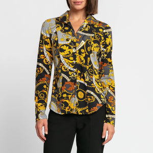 A person is elegantly dressed in the HINSON WU - DONNA SHIRT, showcasing its ornate baroque pattern in black, yellow, gray, and white. Paired with black pants, the stretch polished cotton fabric of this shirt from HINSON WU enhances the sophisticated look against a plain white background.