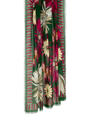 The FRANCO FERRARI - NYMPHAEA WOOL SCARF by FRANCO FERRARI is a long, rectangular scarf crafted in Italy. It features a green background adorned with large red, white, and beige Nymphaea print flowers and leaves. The edges have a slightly fringed finish and are bordered with horizontal red stripes that complement the floral design.