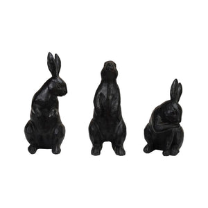 The CREATIVE COOP RESIN RABBIT WITH CAST IRON FINISH set features three dark sculptures: one sitting upright with alert ears, another standing tall on its hind legs, and the third grooming itself.