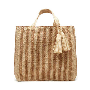 The MAR Y SOL - AMALFI TOTE BAG by MAR Y SOL is a yellow and white striped woven bag with two short handles and a large beige tassel near the top. It features a rectangular shape and textured fabric, offering a chic silhouette that exudes a handcrafted look.