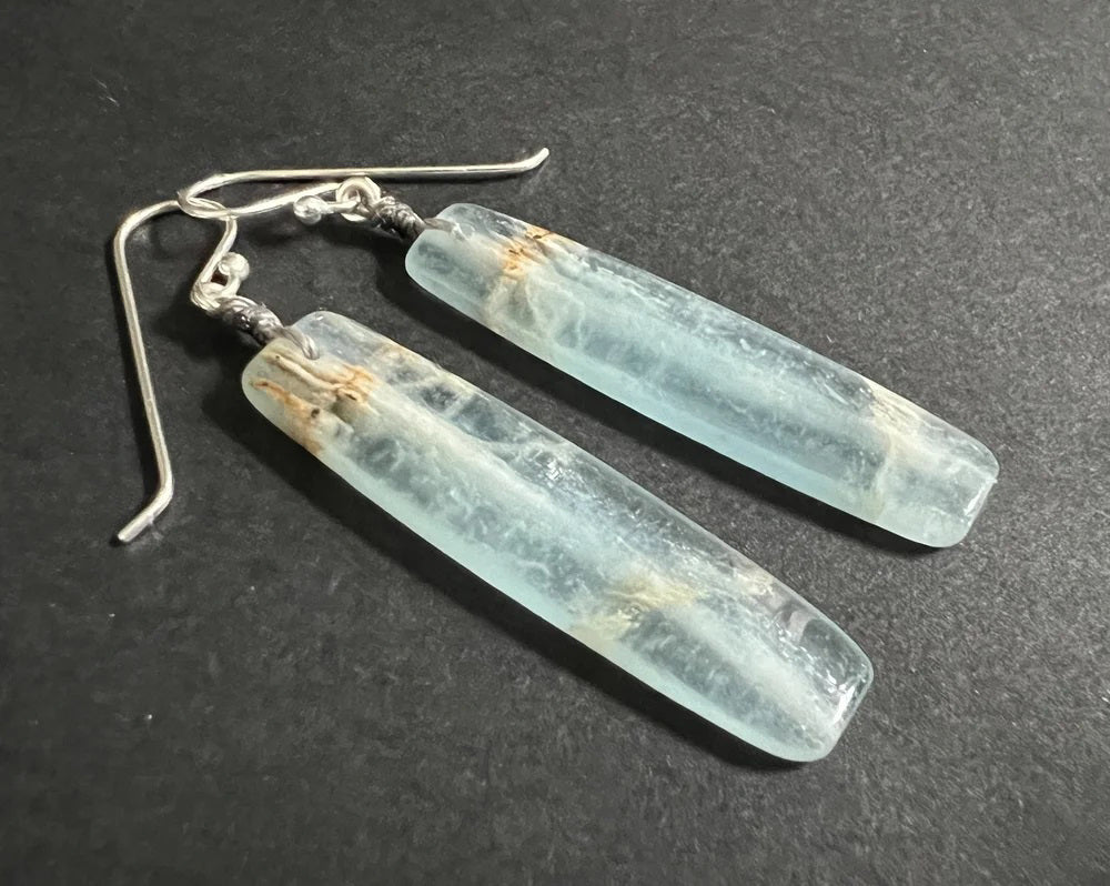 The ANN LIGHTFOOT - BLUE CALCITE SLAB EARRINGS feature long, rectangular, translucent blue-green calcite stones with natural streaks, suspended from sterling silver earwires against a plain white background.
