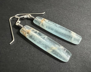 The ANN LIGHTFOOT - BLUE CALCITE SLAB EARRINGS feature long, rectangular, translucent blue-green calcite stones with natural streaks, suspended from sterling silver earwires against a plain white background.