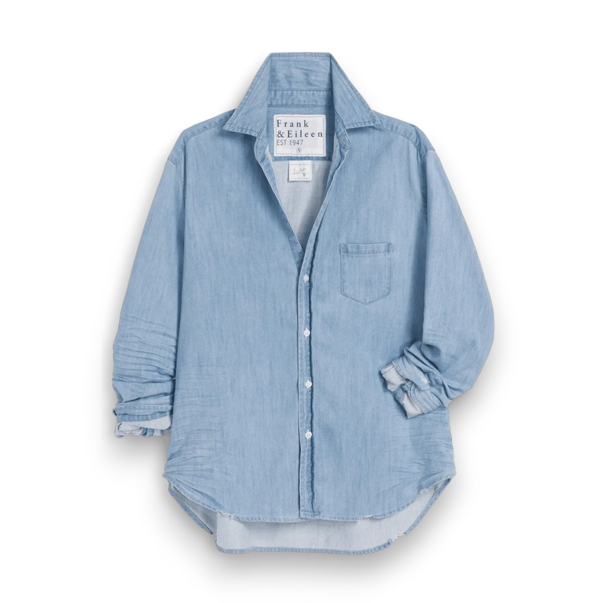 The FRANK &amp; EILEEN Eileen Relaxed Button Up in Famous Denim Classic Wash is a light blue, long-sleeve shirt with bust-flattering buttons, a chest pocket, rolled sleeves, and a curved hem, shown against a white background.