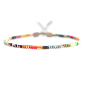 The JULIE ROFMAN - MINI BRACELET by JULIE ROFMAN JEWELRY is a vibrant handwoven piece adorned with small, square beads in various shades of pink, red, and white. It is displayed against a white background and includes a straightforward sterling silver clasp for convenient fastening.