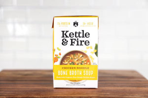 A box of KETTLE & FIRE Chicken Noodle Soup, showcasing 11 grams of protein per serving. Made with organic chicken meat and free-range chicken bones, it weighs 16.9 oz (479g) and features a rich, 14+ hour simmered bone broth with organic noodles.