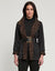 A woman with long dark hair is wearing the HINSON WU Constance Reversible Jacket, which features stylish leopard print details on the collar and belt. She pairs it with a black turtleneck top and pants while standing against a light background. The look balances style with practicality, as the jacket is conveniently machine washable.