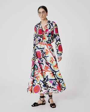 The SFIZIO - FRIDA SKIRT by SFIZIO is a mid-length, versatile garment with a white background that showcases a bold and colorful abstract floral pattern in shades of red, blue, yellow, and green. Made in Italy, this skirt features pleats and a flared silhouette for an effortlessly chic look.