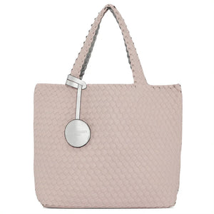 The WOVEN REVERSIBLE TOTE BAG by LINES OF DENMARK is a white tote featuring two shoulder straps and a circular faux-leather tag on one strap. This shopper showcases a textured, interlaced pattern and reversible design, providing stylish and elegant dual styling options. The image background is plain white.