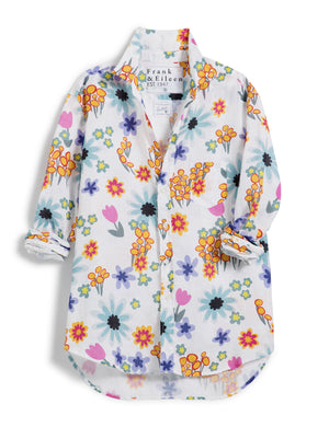 A white long-sleeve Eileen Relaxed Button Up Shirt in Hot Pink Floral by Frank & Eileen, featuring a vibrant floral print with various flowers in shades of yellow, orange, pink, blue, and purple. This classic linen shirt has a classic collar, button-down front, and rolled-up sleeves. A visible label inside reads "Frank & Eileen EST 1947".