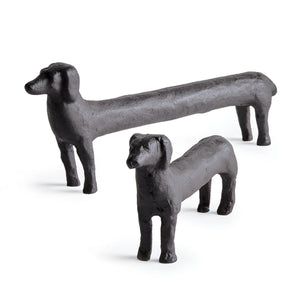 The NAPA HOME AND GARDEN - CONNLEY DOG features two elongated cast aluminum dachshund sculptures against a white background. The front sculpture is shorter, with the longer one behind it, showcasing their exaggerated forms—ideal for unique home decor.