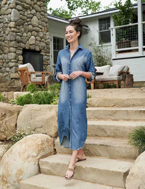 The FRANK & EILEEN Rory Maxi Shirtdress in Famous Denim is a full-length button-up dress featuring a collar, rolled-up sleeves to mid-length, and a single chest pocket. Its sleek, minimalist design embodies that California chic look against a plain white textured background.