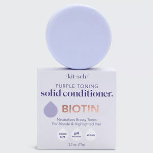 A light purple solid conditioner bar sits atop a white rectangular box. The box, labeled "KITSCH Purple Toning Solid Conditioner Bar," highlights that the biotin-infused product, weighing 2.7 oz (77g), neutralizes brassiness in blonde and highlighted hair.