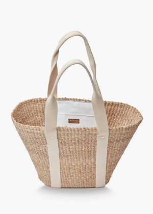 The KAYU Toci Medium Tote by KAYU features a wide, woven abaca straw body with sturdy cotton handles. Its minimalist design is highlighted by two vertical beige straps on both sides, combining style and functionality.