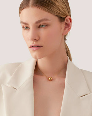 The JENNY BIRD - AURORA PENDANT NECKLACE by JENNYBIRD showcases a delicate chain with a luminous sphere pendant made from high-polish gold, displayed against a plain white background.