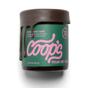 A jar of COOP'S - VEGAN HOT FUDGE with chocolate dripping from the lid. The label is green with pink cursive text and states "Smooth Rich Flavor," "High-grade European chocolate with fresh extracted coconut," and "New Look." This handmade chocolate sauce is the best ice cream topping. Net weight 10oz (283.5g).