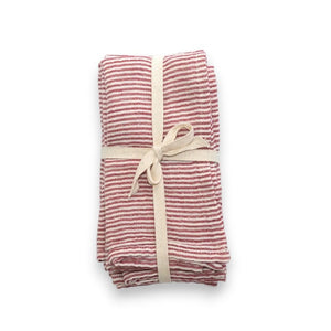 The RED STRIPE CLOTH NAPKIN by CREATIVE COOP is crafted from red and white striped cotton fabric, intricately folded into a bow shape. It is adorned with small red berries and green leaves, measures 18" x 18", and includes a small white tag. This delightful napkin is available for individual purchase and displayed on a light gray surface.