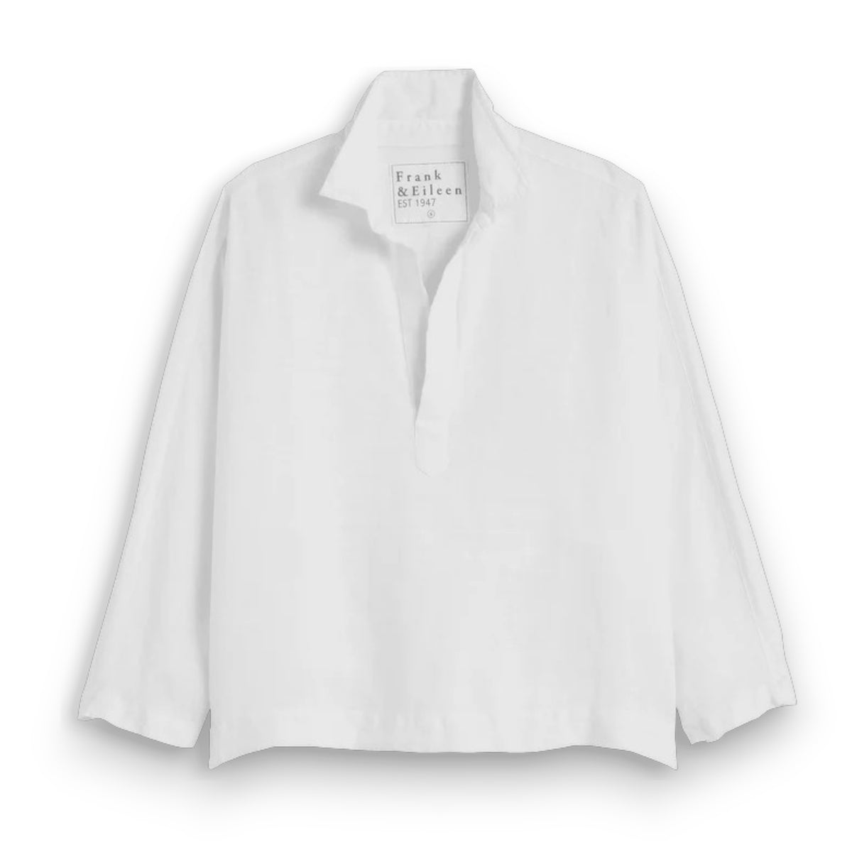 A woman with long brown hair smiles outdoors, wearing the FRANK &amp; EILEEN Gabi Popover Shirt in washed linen white. Green leafy plants and wicker furniture are visible in the background.