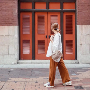 The LAMBWOLF COLLECTIVE - FORAGER DOG BUM BAG is a beige crossbody sling bag featuring a stylish mesh design on the front. It comes with a long, adjustable strap secured by a buckle. The front of the bag includes snap buttons for closure along with a quick-access pouch and is made from lightweight, durable material.