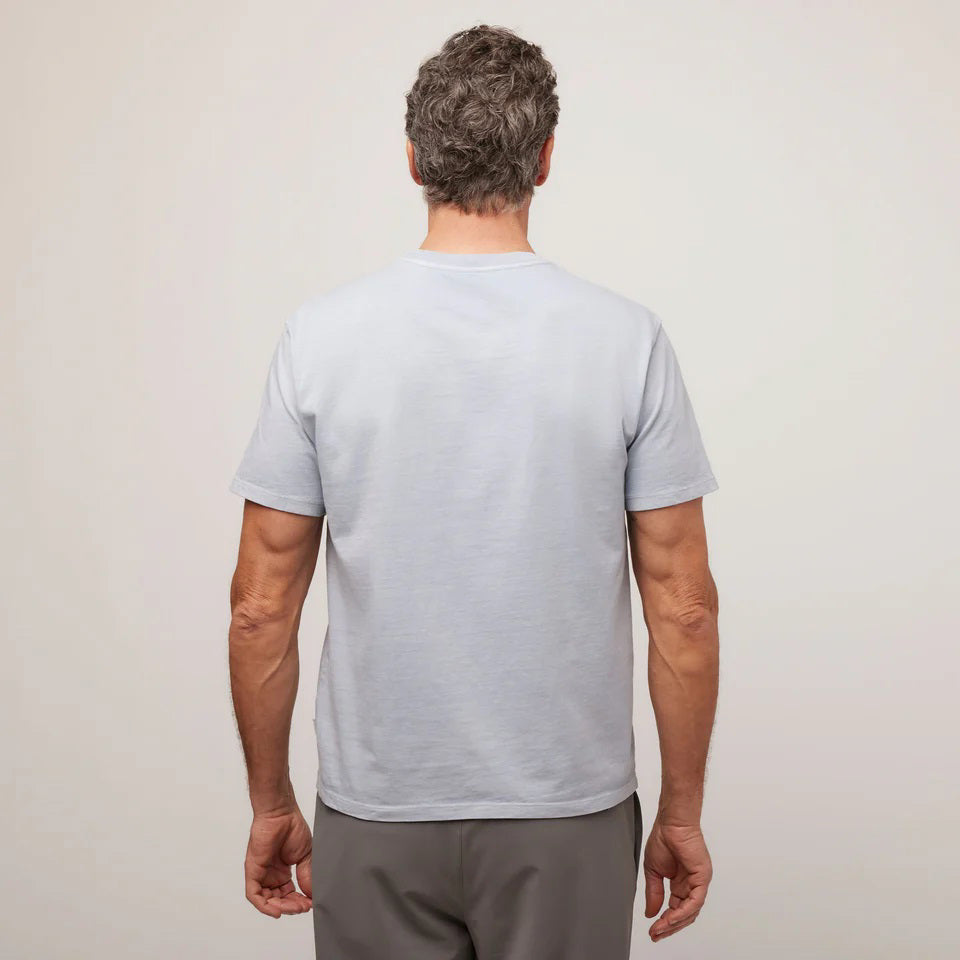 A middle-aged man with short gray hair wears the TILLEY Mid Weight Sun Washed T-Shirt in Ice Blue, standing against a plain light background and looking confidently at the camera.