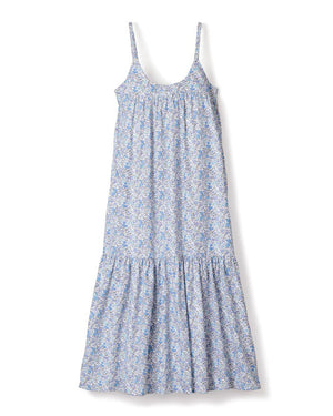 The PETITE PLUME - Fleur d'Azur Chloe Nightgown is a sleeveless, knee-length sundress with thin straps, showcasing a beautiful blue and white floral pattern. Crafted from the finest quality cotton, this dress offers a loose, flowy fit and features a gathered section near the bottom hem, giving it a slightly ruffled look reminiscent of traditional nightwear from PETITE PLUME.