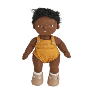 A DINKUM DOLL from OLLI ELLA USA features soft brown hair and comes dressed in a white knit romper paired with brown shoes. This charming doll has an embroidered face with brown eyes, a small nose, and a gentle smile. Its posable body makes it perfect for imaginative playtime, and it is posed standing upright.