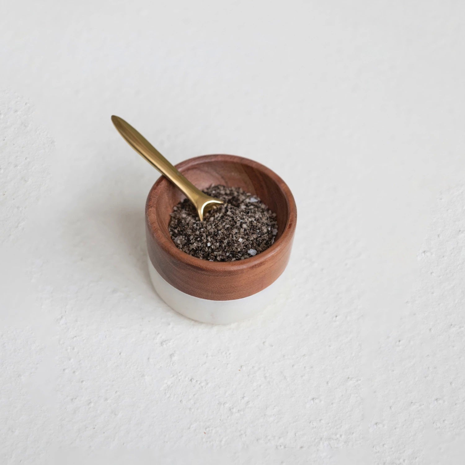 The MARBLE AND ACACIA PINCH POT by CREATIVE COOP is a small, round bowl combining acacia wood and ceramic. It features a sleek brown finish on the top half and white ceramic on the lower half, offering a simple yet contemporary design reminiscent of a modern pinch pot.