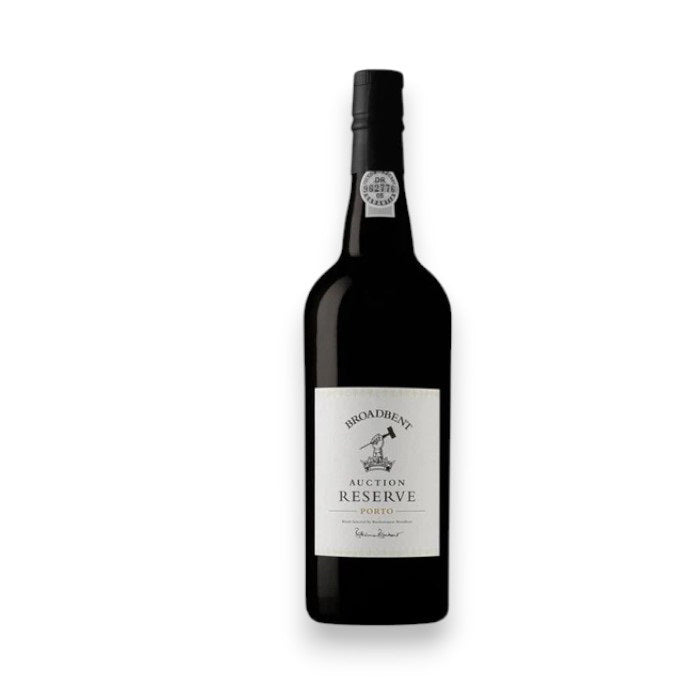 A dark glass bottle of BROADBENT AUCTION RESERVE PORT by WINE: WINEBOW, featuring a white label with black text, stands upright against a plain white background, evoking notes of blackberry jam and dark chocolate.