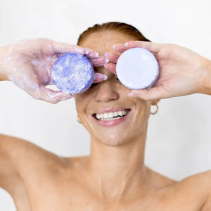 A light purple solid conditioner bar sits atop a white rectangular box. The box, labeled "KITSCH Purple Toning Solid Conditioner Bar," highlights that the biotin-infused product, weighing 2.7 oz (77g), neutralizes brassiness in blonde and highlighted hair.