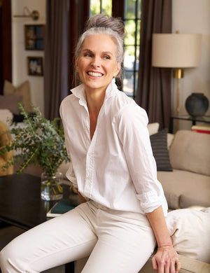 A FRANK AND EILEEN - FRANK CLASSIC BUTTON-UP SHIRT SUPERFINE POPLIN in white, featuring a classically tailored long-sleeve design with rolled-up sleeves, is displayed against a plain, textured background. The label inside the collar reads "FRANK & EILEEN." This shirt offers a classic, slightly relaxed fit with a curved hemline and bust-flattering button placement.