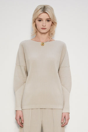 A person with shoulder-length blonde hair stands with their back to the camera, showcasing the MEIMEIJ Pleated Top from MEIMEIJ. The beige ribbed outfit features wide sleeves and a boat neck, set against a plain, light-colored background that complements its elegance.