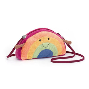 Product Description: The AMUSEABLE RAINBOW BAG by JELLY CAT is an open, vibrant crossbody bag featuring a rainbow pattern. It includes a sturdy magenta zipper, pink lining, and a strong webbed strap. Inside, a tag with the "Llamacorns" logo is attached. The bag also has two small brown ears near the top for added charm.