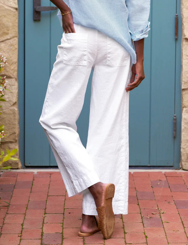The FRANK AND EILEEN - WEXFORD WIDE LEG LINEN TROUSER IN WHITE from FRANK &amp; EILEEN is a stylish pair of wide-leg pants made from lightweight Italian Performance Linen. These white trousers feature a mid-rise waist, a concealed front zipper, and side pockets, all with a straight and relaxed fit that extends to the hem.