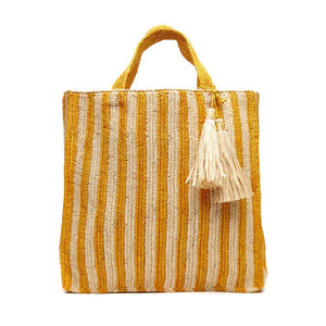 The MAR Y SOL - AMALFI TOTE BAG by MAR Y SOL is a yellow and white striped woven bag with two short handles and a large beige tassel near the top. It features a rectangular shape and textured fabric, offering a chic silhouette that exudes a handcrafted look.