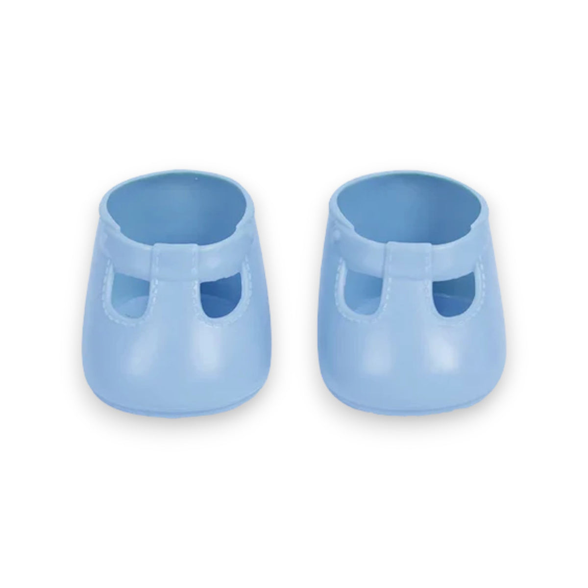 A close-up of a baby wearing OLLI ELLA USA DINKUM DOLL SHOES in Mallow Pink and white socks. The baby is seated on a soft, pale pink textured blanket, dressed in light brown clothing. Only the lower half of the baby&#39;s body is visible.