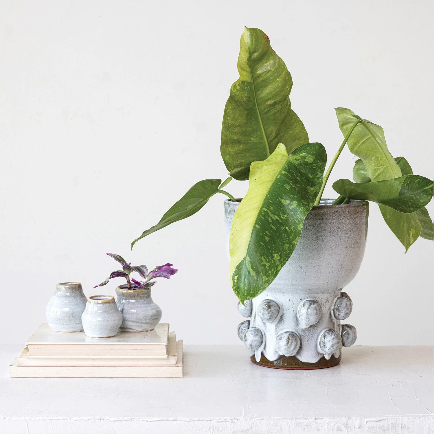 Three small TERRACOTTA GLAZED VASES by CREATIVE COOP, round with a smooth reactive glaze in white and light brown, are displayed in a row. Each piece varies slightly in shape and size, enhancing their unique handcrafted look.