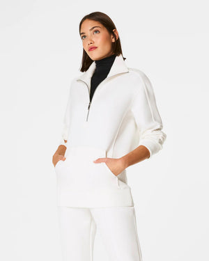 A person with shoulder-length hair faces away from the camera, showcasing the SPANX - AIRESSENTIALS LUXE HALF ZIP TUNIC in super-soft spacer fabric. This set offers bum coverage and blends style with comfort against a plain white background.