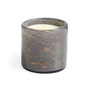 A LAFCO - Feu de Boise Holiday Candle, nestled in a marbled glass holder and infused with the essence of Virginia Cedarwood, rests on a dark surface beside its sophisticated gray and gold textured box inscribed with "LAFCO New York, Feu de Bois, woodfire." The setting is gently illuminated to emphasize the candle's warm glow.