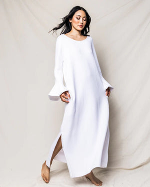 A long-sleeved white PETITE PLUME - LUXE PIMA NIGHTGOWN, crafted from Peruvian Pima cotton, hangs against a white background. The nightgown features a round neckline and flared sleeves with ruffled cuffs. With a subtle quilted effect and simple, elegant design, it exudes the charm of luxurious sleepwear.