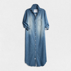 The FRANK & EILEEN Rory Maxi Shirtdress in Famous Denim is a full-length button-up dress featuring a collar, rolled-up sleeves to mid-length, and a single chest pocket. Its sleek, minimalist design embodies that California chic look against a plain white textured background.