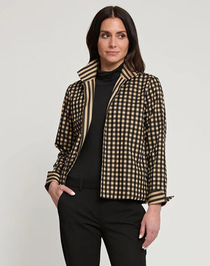 A woman with long dark hair is wearing the HINSON WU - MOLLY Long Sleeve Reversible Jacket, which features high-collared, black and beige vertical stripes, over a black turtleneck. She stands against a plain light background, looking straight at the camera, with her hands holding the jacket lapels.