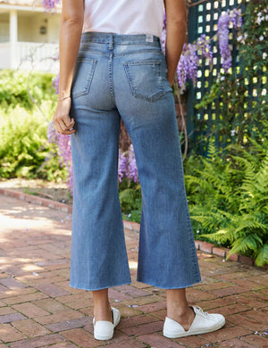 The FRANK & EILEEN Galway Gaucho Jean in the 1972 Wash offers a high-waisted, wide-leg design with a subtle faded effect and classic five-pocket styling, perfectly embodying the spirit of Italian Dream Denim. Featuring a raw hem for that iconic gaucho-style, these light blue jeans are showcased against a lightly textured background.