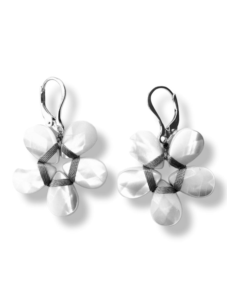 The ANN LIGHTFOOT - MOTHER OF PEARL FLOWER EARRINGS by ANN LIGHTFOOT feature petal-shaped mother of pearl beads arranged in a circular pattern with dark wrapping in the center. Crafted from sterling silver, these earrings come with lever back earwires for secure fastening against a white background.