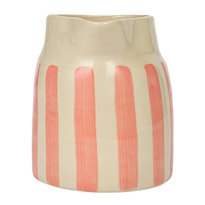 Two Creative Coop 1 3/4 Quart Pitchers with vertical stripes, one featuring blue and orange hues and the other in pink, rest elegantly on a stack of books atop a light-colored surface. The neutral background ensures that these vibrant hand-painted stoneware pitchers take center stage.