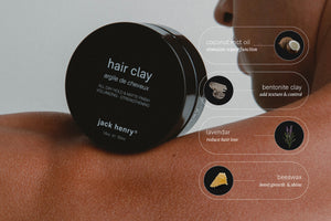 A round black JACK HENRY - HAIR CLAY container rests on a shoulder. An infographic shows coconut MCT oil, bentonite clay, lavender, and beeswax as ingredients with illustrated hair growth benefits.