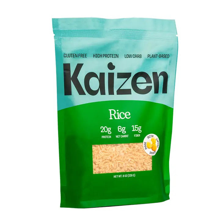 A green and light blue bag of KAIZEN - RICE by KAIZEN FOOD COMPANY is displayed. The packaging highlights key features such as being gluten-free, high protein, low carb, keto-friendly, and plant-based. The bag contains 8 ounces (226g) of rice with 20g of protein, 6g net carbs, and 15g fiber per serving.