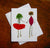 Introducing the TOGETHER CARD by PETAL PEOPLE PRESS: This enchanting botanical note card features two whimsical figures crafted from dried flowers and leaves, holding hands in a display of natural elegance. One figure is adorned with an orange petal skirt and a green leaf top, while the other showcases a purple body topped with a brown flower head. Their slender green stems serve as limbs against the crisp white background, creating a charming visual that captures the beauty of nature.